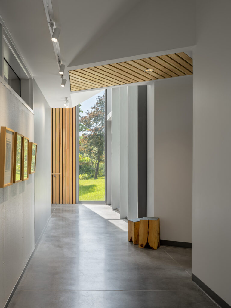 View down a hallway ending in a large window of an academic building with wood details.