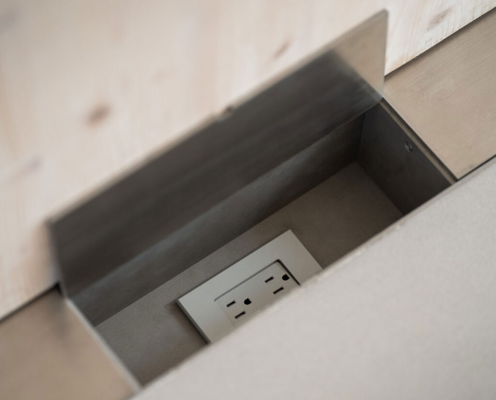 Image of metal electrical chase inset into floor to house outlet.