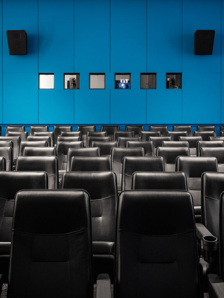 Theater with leather seats and bright blue wall.